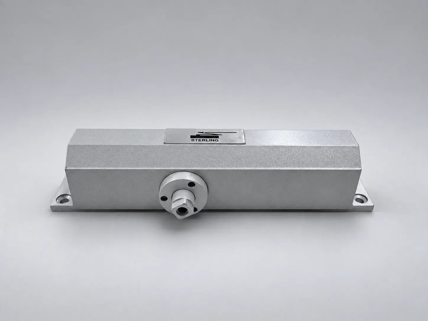 Sterling DC 1500 door closer body, front view with the label plate on the top face and the spindle, studio photograph