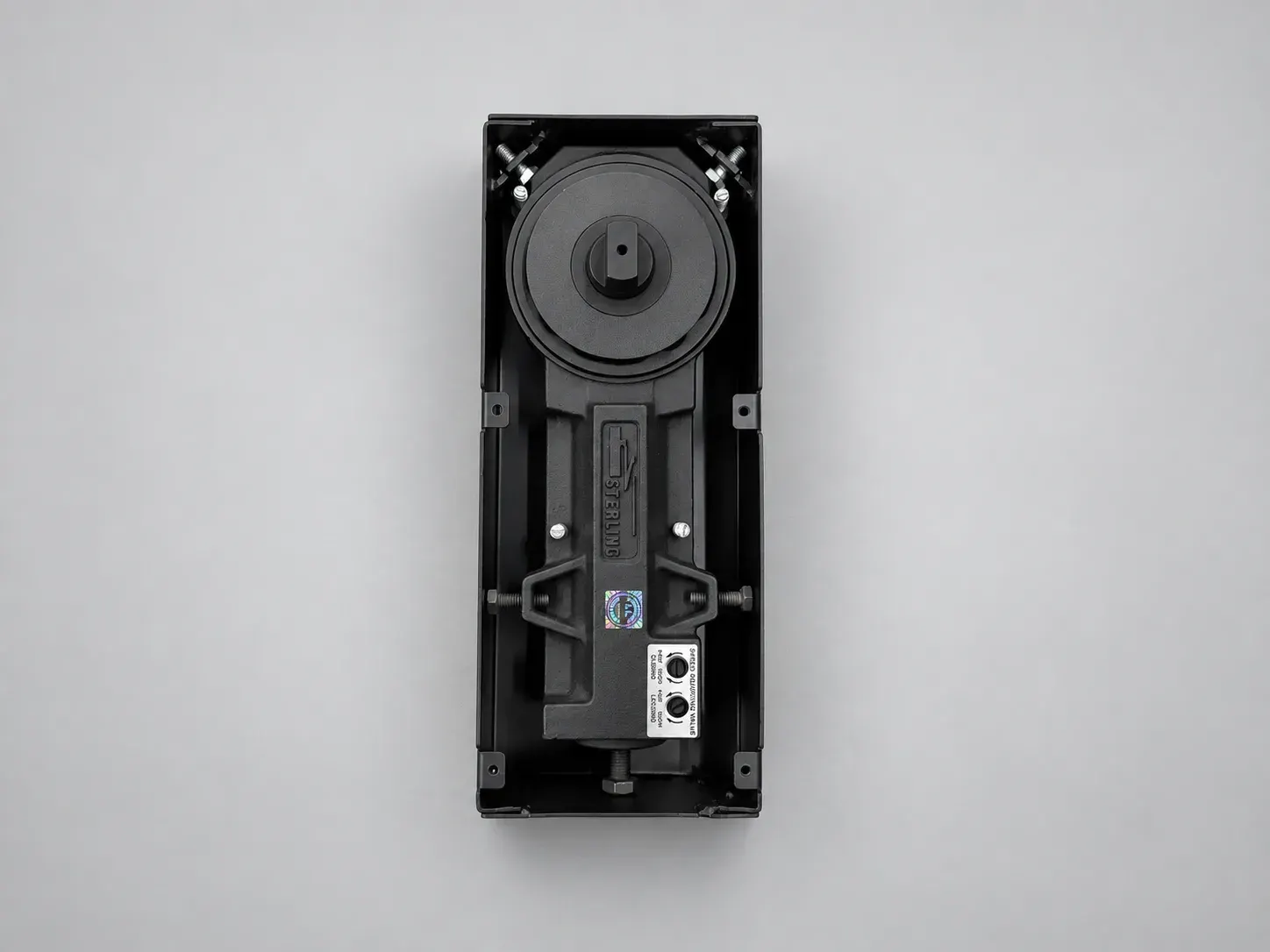 Sterling FS 1000 floor spring inside a black box, cover plate removed, overhead view, studio photograph